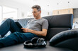 © Josep Rovirosa/Westend61 - Mature man using digital tablet while sitting on sofa in living room
