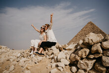 Egypt, Cairo, Two Female Tourists Sitting Together On Rocks With Great Pyramid Of Giza In Background