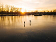© Konstantin Trubavin/Westend61 - Friends skating on frozen pond during sunset