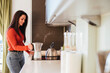 © DREAMSTOCK1982/Westend61 - Smiling woman preparing coffee in kitchen at home