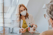 © Mareen Fischinger/Westend61 - Doctor with protective face mask explaining patient over eye model at clinic