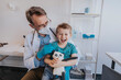 © Mareen Fischinger/Westend61 - Male pediatrician looking at cheerful boy with toy while sitting at medical examination room