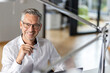 © peter scholl/Westend61 - Smiling businessman holding pen in office