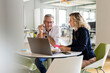 © peter scholl/Westend61 - Male and female entrepreneur with laptop sitting at table during meeting in office