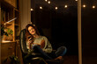 © VITTA GALLERY/Westend61 - Smiling woman with book using smart phone while sitting at home