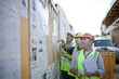 © LOUIS CHRISTIAN/Westend61 - Three male construction workers inspecting bulletin board at construction site
