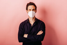 Mid Adult Businessman Wearing FFP2 Face Mask Standing With Arms Crossed Against Colored Background