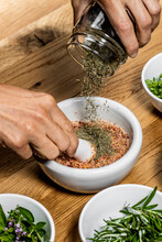 Woman Pouring Herbs In Mortar And Pestle While Preparing Spice
