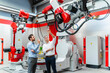 © Daniel Ingold/Westend61 - Mature entrepreneur discussing over robotic welding torch with colleague in factory