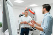 © Daniel Ingold/Westend61 - Young male engineer explaining business plans to mature entrepreneur at white board in factory