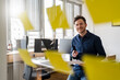 © Daniel Ingold/Westend61 - Smiling businessman with document looking at adhesive notes at office