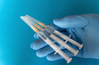 © Stefan Rupp/Westend61 - Hand of person wearing protective glove holding three syringes