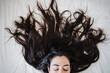 © Eva Blanco/Westend61 - Woman with long hair lying on bed at home