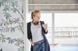 © Jo Kirchherr/Westend61 - Woman with hand in pocket holding coffee cup while leaning on wall at home