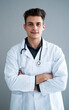 © Giorgio Fochesato/Westend61 - Male handsome doctor with arms crossed against gray wall