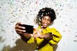 © Giorgio Fochesato/Westend61 - Young woman taking selfie through mobile phone while standing amidst confetti against white background