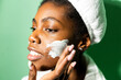 © Giorgio Fochesato/Westend61 - Close-up of woman applying cream on face while standing against green background