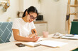 © Giorgio Fochesato/Westend61 - Smiling woman writing in book at home