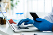 © Giorgio Fochesato/Westend61 - Scientist holding smart phone while using laptop at desk in laboratory