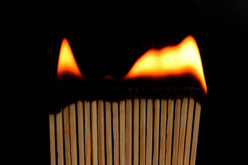 Burning matches standing in a row on a black background