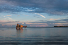 Cedar Key, FL: A Weathered Old Shack Stands Alone In The Gulf Of Mexico During Sunset