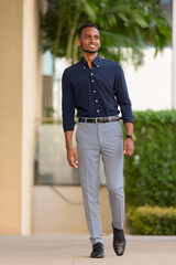 Full length shot of handsome African businessman outdoors walking and smiling