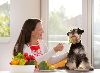 Woman feeding dog with vegetables