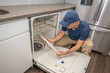 © spatesphoto - Appliance repairman working on a broken dishwasher