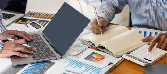 A confident young businessman who analyzes graph data using a computer while spending time in the office.
