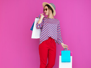 Young woman with shopping bags on pink background