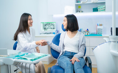 Wall Mural - Caucasian girl patient greeting dentist by making handshake in clinic.