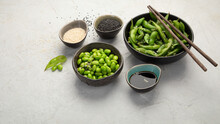 Raw Edamame Soya Beans With Salt And Sauce On Light Gray Background.