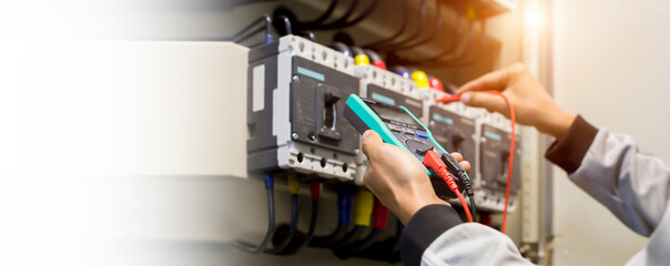 Wall Mural - Electrical engineer tests the operation of the electric control cabinet on a regular basis for maintenance.