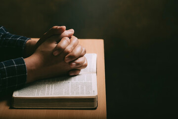 Wall Mural - Hands of praying young man and Bible on a wooden desk background.man join hands to pray and seek the blessings of God, the Holy Bible.