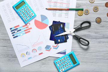 Poster - Scissors with credit cards, calculators and documents on grey wooden background. Concept of bankruptcy