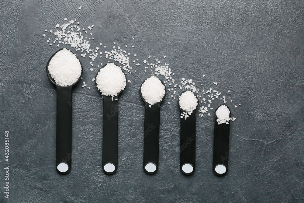 Measuring spoons with salt on dark background
