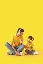 Father And Little Son Listening To Music On Color Background