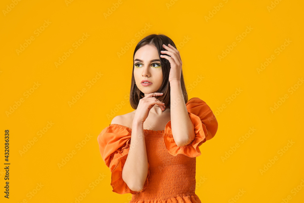 Stylish young woman on yellow background