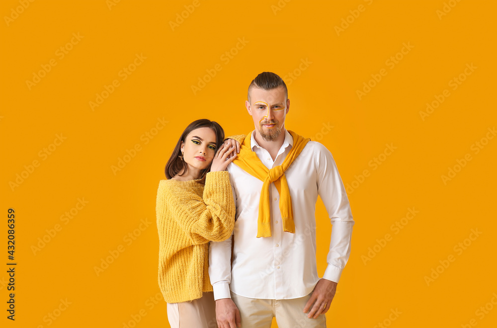 Stylish young couple on yellow background
