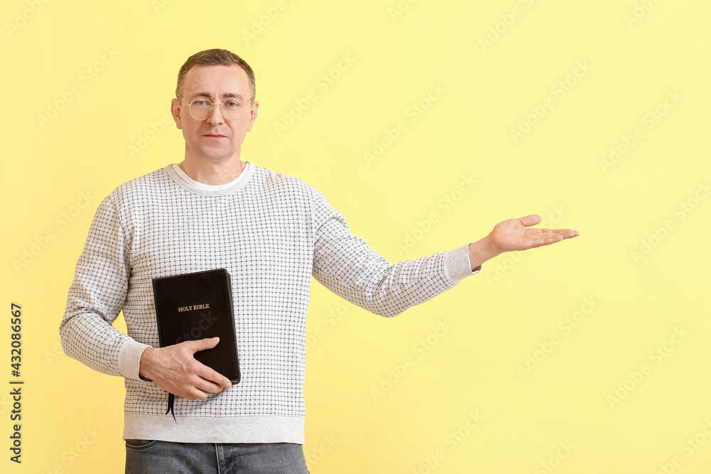 Man with Bible showing something on color background