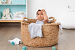 © Lisa Tichané - Funny baby sitting in laundry basket with clothes on head