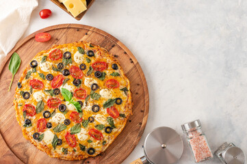 Italian pizza on a wooden board with ingredients tomatoes, cheese and a pizza knife. Top view on a light table. Banner with space for inscriptions or advertising