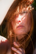© ullision - Sensual sexy portrait of young beautiful redhead woman shading her face with her arm in the sunlight, copy space