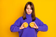 Photo of sweet doubtful young woman wear purple pullover holding citrus halves cover boobs isolated yellow color background