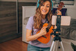 Online ukulele lessons. A modern woman watches video tutorials/learn students how to play instrument online.