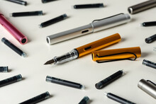Ink Pens And Ink Cartridges Are Scattered On The Table.