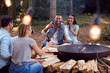 © Monkey Business - Group Of Friends Camping Sitting By Bonfire In Fire Bowl Celebrating And Drinking Beer Together