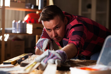 Wall Mural - Woodworker measuring wooden plank. Young man working in workshop