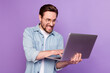 Photo of unhappy angry young man look hold laptop write letter work isolated on purple color background