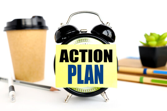 Action plan. there is a sticker on the alarm clock. against the background of a paper cup with coffee and plants in a pot. alarm clock on white background